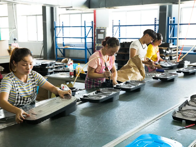 Workers assembling appliance components at a workbench