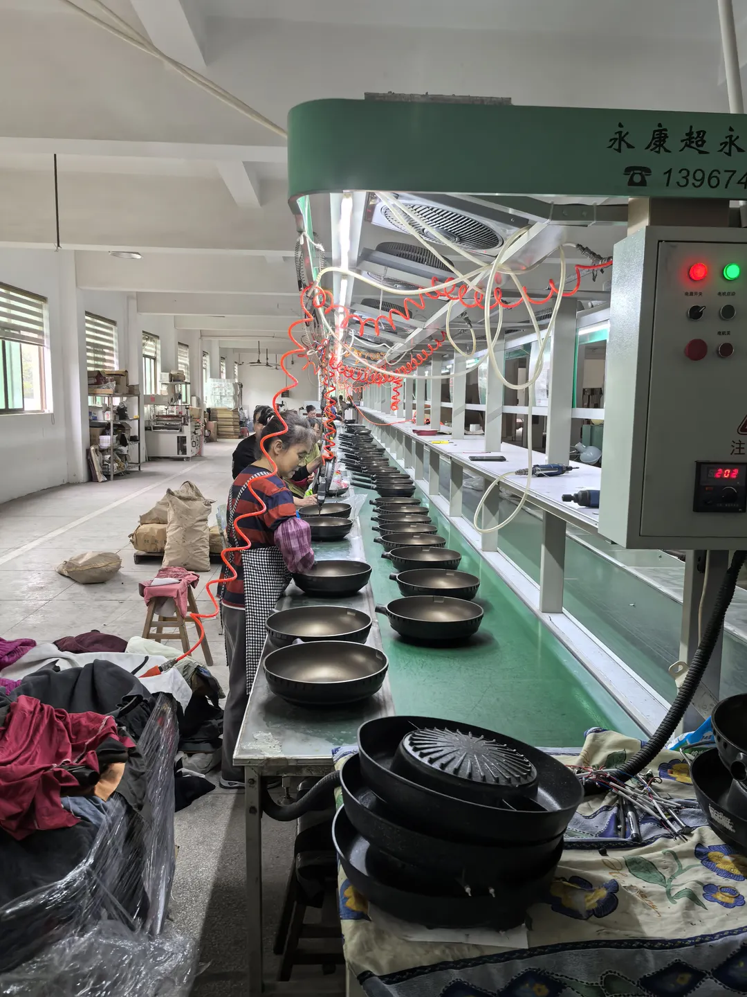Cookware on a conveyor beside assembly workstations