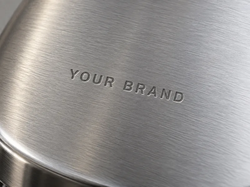 Stamping concept with shallow recessed YOUR BRAND lettering in brushed steel.