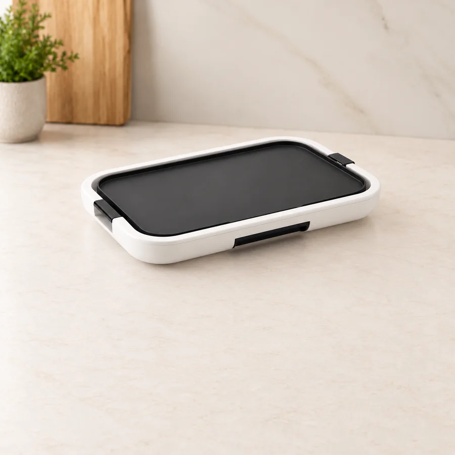 White electric tabletop grill with a smooth cooking plate.